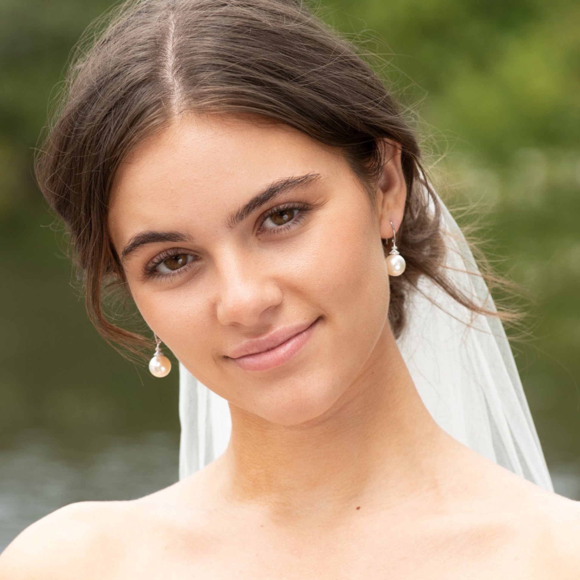 a portrait of a bride wearing a pair of pearl earrings